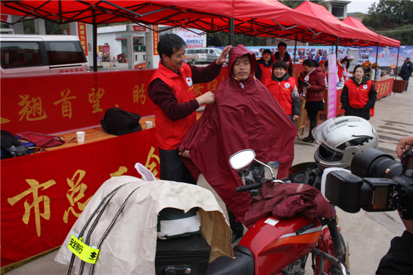 梧州市總工會(huì)的黨員義工們?cè)谑袞|出口春運(yùn)服務(wù)站助力&ldquo;摩托大軍&rdquo;平安返鄉(xiāng)，幫助他們檢查車(chē)輛和行李，穿上雨衣。--黃賀峰攝.j